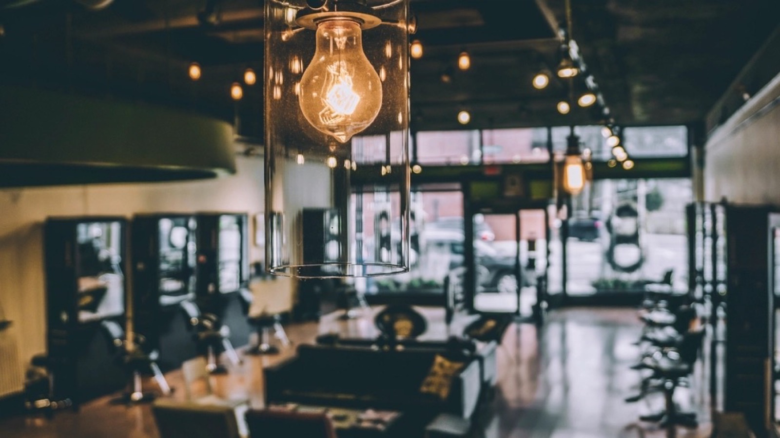 Barbershop met kappersstoelen, spiegels en hanglampen bij daglicht