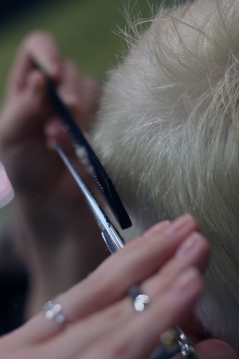Handen met schaar en kam die blond haar bijknippen